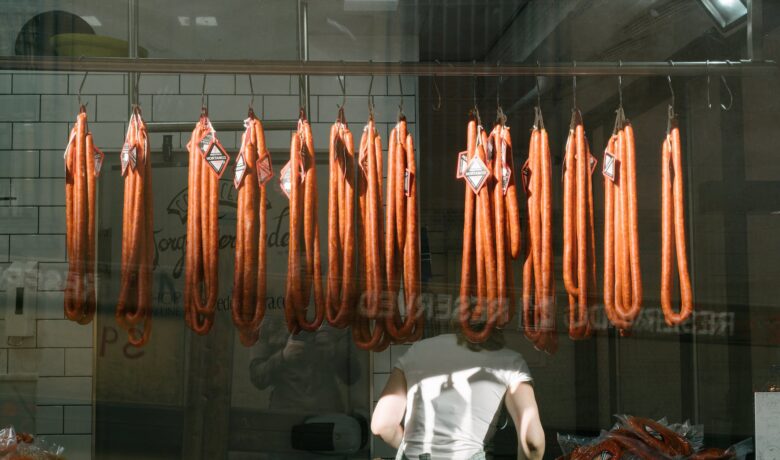 anonymous worker with long sausages at meat processing plant